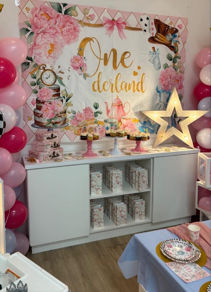 Alice in ONEderland first birthday party theme with pink floral decorations, tea party cake, and balloon garlands at Kids Hideout Fort Lauderdale