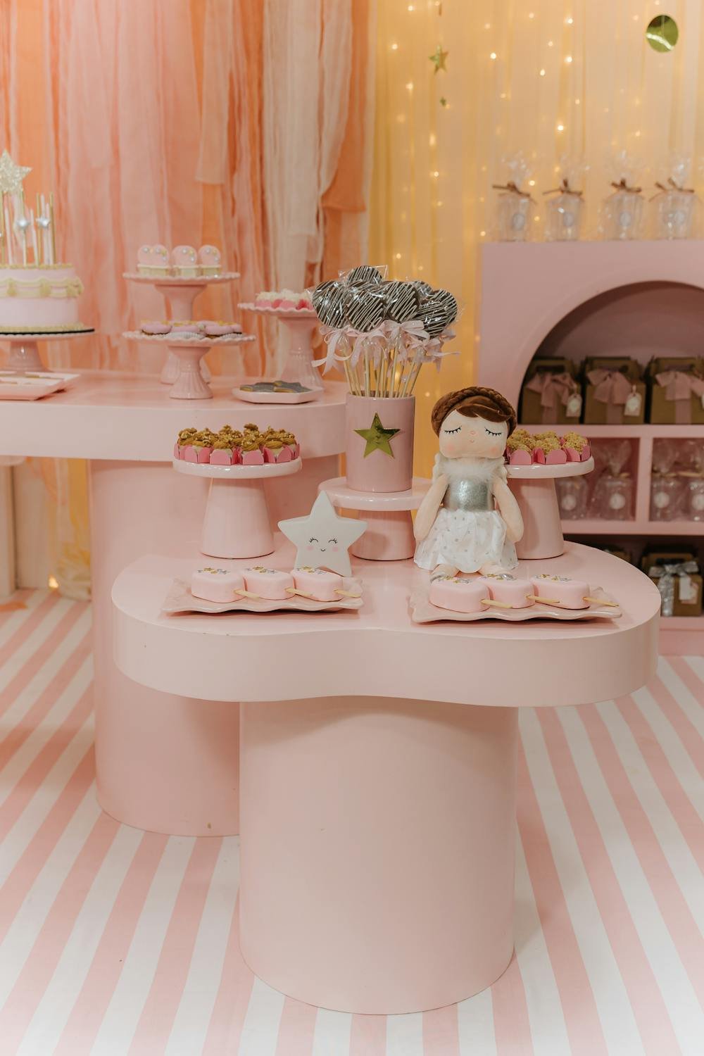 Beautifully decorated pink birthday party setup with sweets and balloon arches at a venue