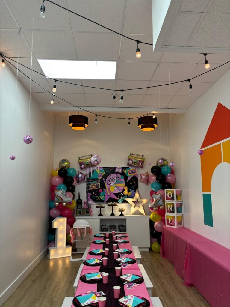 Girls Just Want to Turn ONE birthday party full venue view with 80s retro decor at Kids Hideout