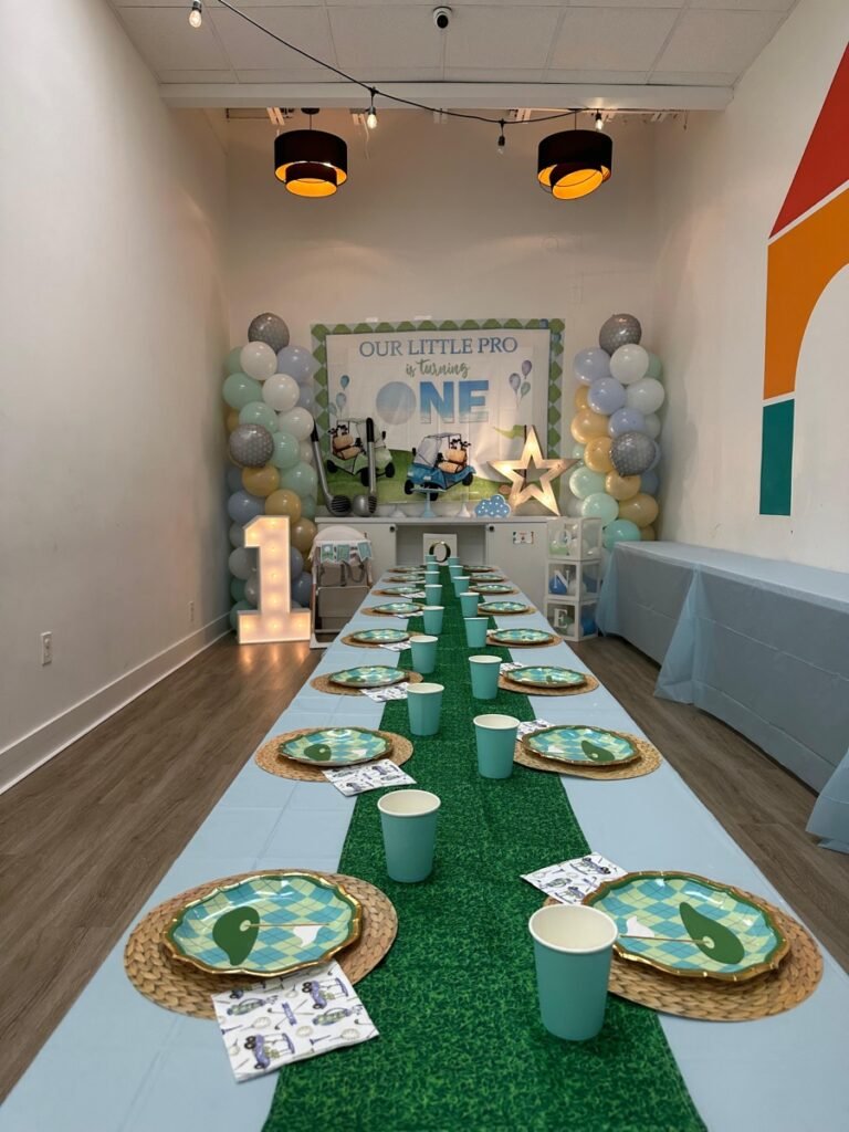 Hole in ONE golf birthday party decorations with mini golf course and flag pin centerpieces at Kids Hideout