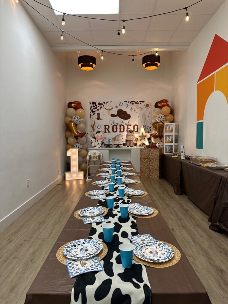 My First Rodeo boy birthday party decorations with cowboy boots, lasso rope, and cactus cutouts at Kids Hideout