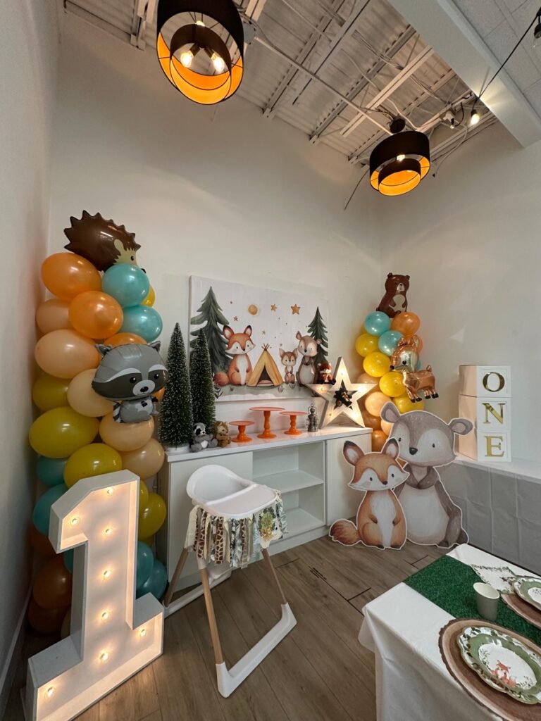 ONE Happy Camper woodland birthday decorations with tent, lanterns, and forest animal accents at Kids Hideout