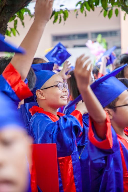 Children wearing graduation gowns at preschool ceremony