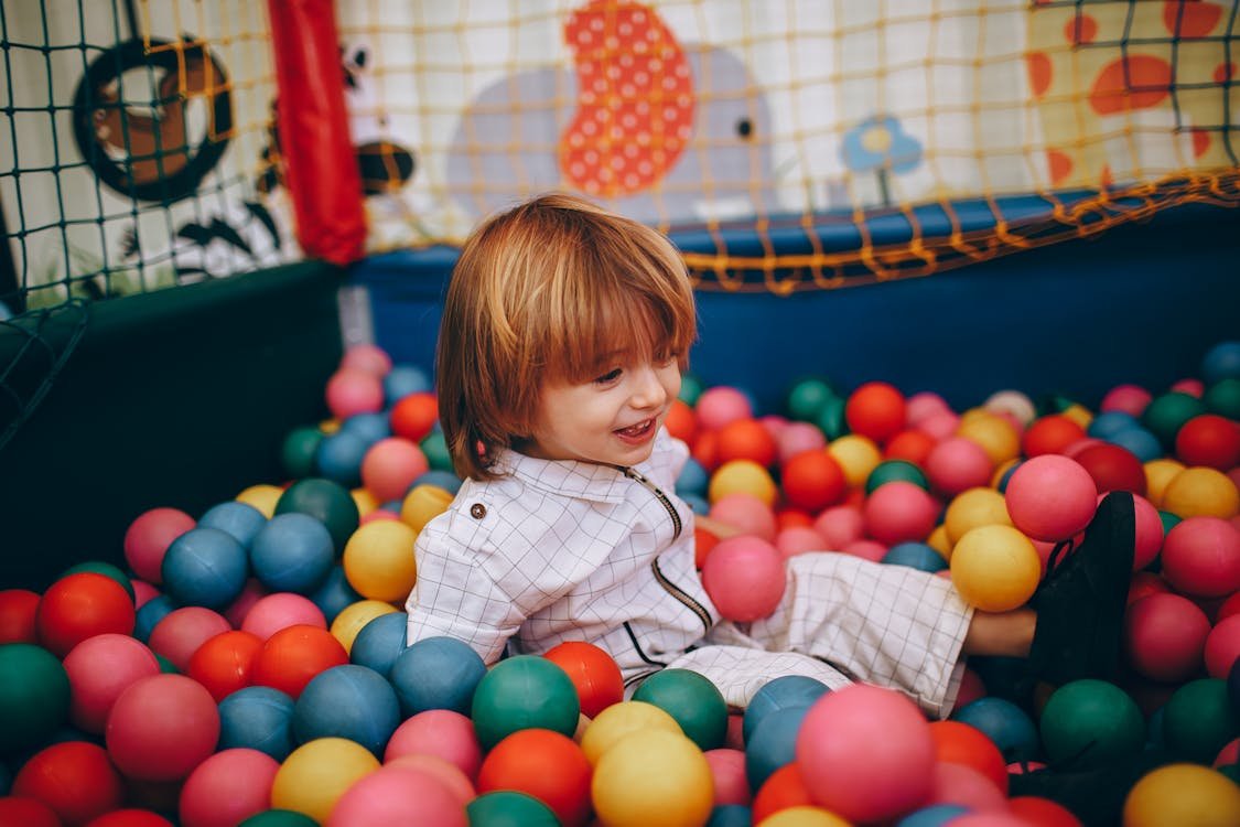 Toddler having fun in a colorful ball pit at an indoor play center in Fort Lauderdale